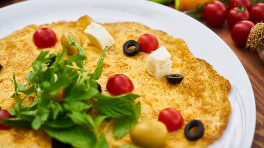 Omelete em um prato branco, com verduras em cima