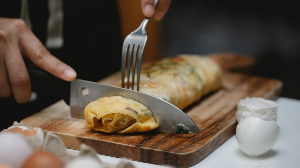 Pessoa cortando omelete enrolado
