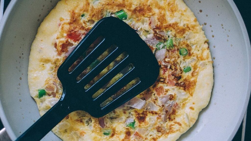 Omelete com uma espátula preta sobre