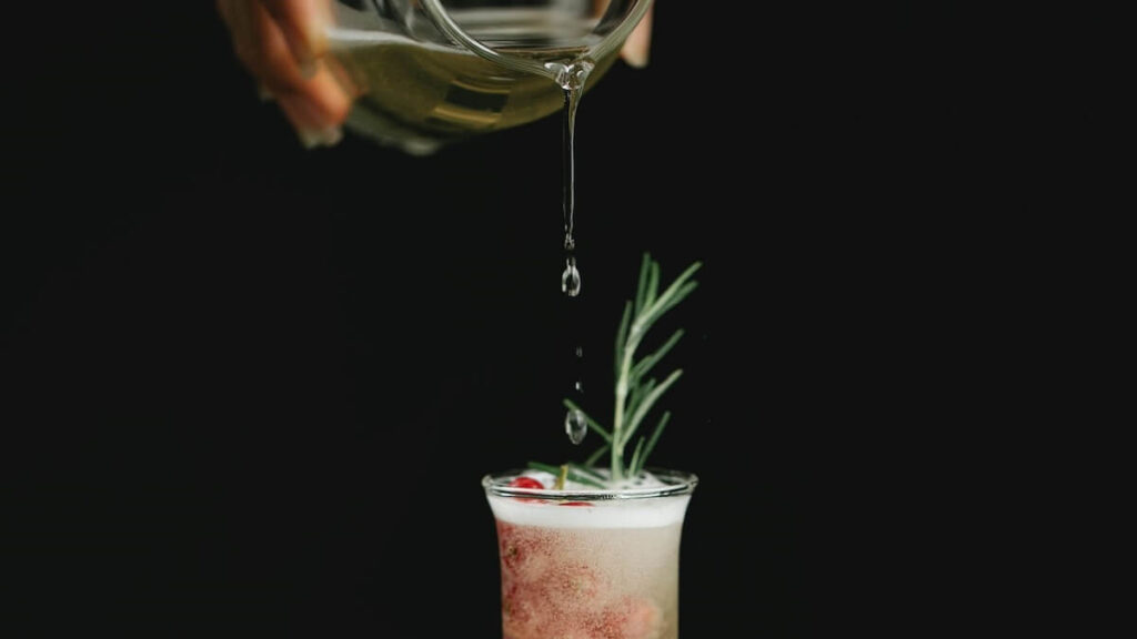 Xarope de açúcar sendo colocado em um drink com fundo preto