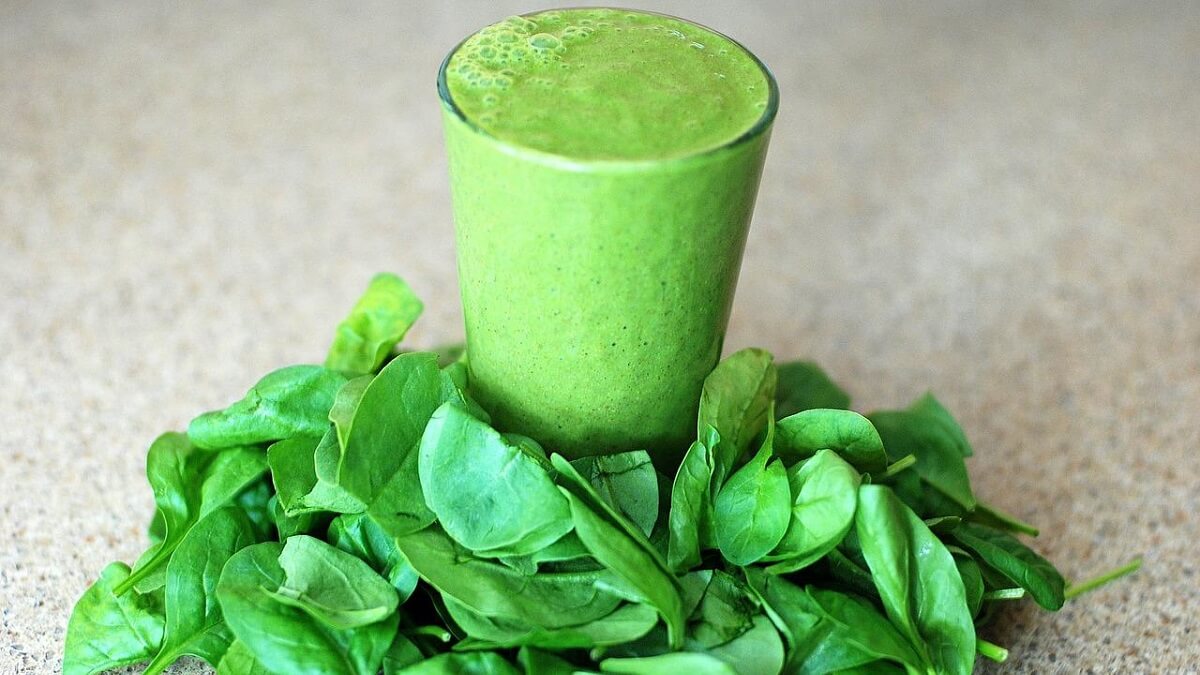 Suco de espinafre com folhas da planta na mesa