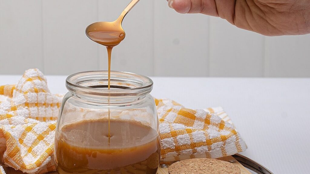 Pessoa pegando doce de leite com uma colher